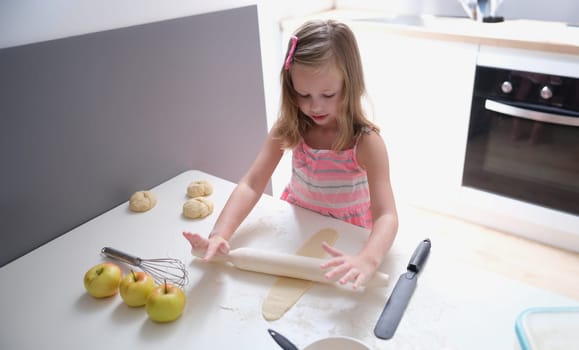 Child girl with rolling pin for baking cookies for dough. Children cooking concept