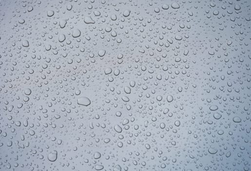 Closeup of raindrops on gray window glass texture background. . Rainy weather concept and natural condensation wallpaper.