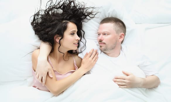 Portrait of lovely couple hugging in bed in morning, well rested family enjoying staying in bed. Lazy weekend, chilling together. Good morning concept