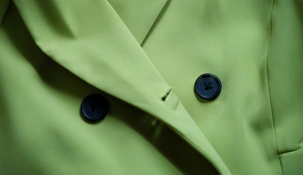 Green stylish suit with black buttons closeup.