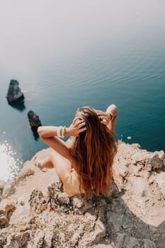 Woman travel sea. Happy tourist taking picture outdoors for memories. Woman traveler looks at the edge of the cliff on the sea bay of mountains, sharing travel adventure journey.