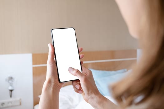 closeup of female hands using smartphone in hotel room , white blank screen for mockup