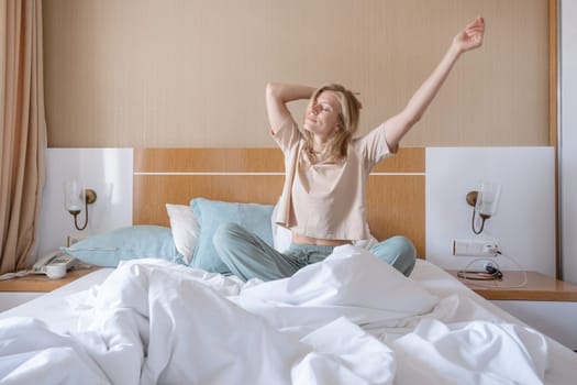 Woman stretching in bed after wake up, sun shines from the window
