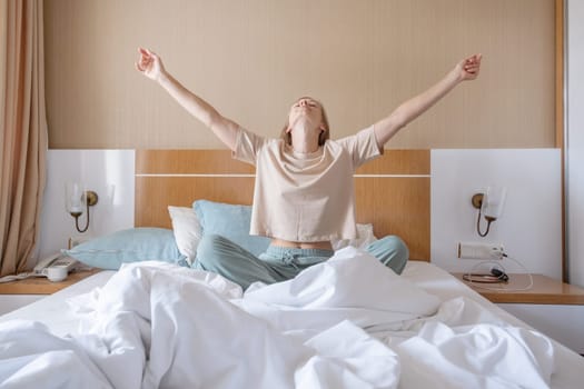 Woman stretching in bed after wake up, sun shines from the window