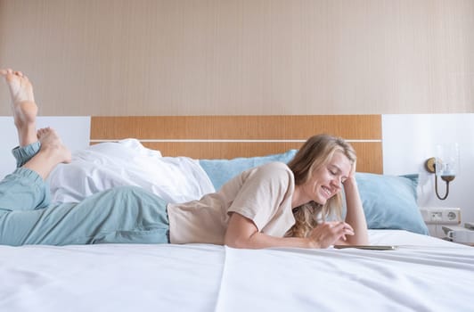 Woman lying in bed after wake up, using smartphone