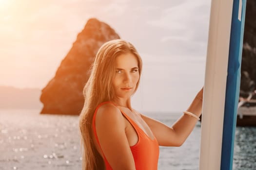 Close up shot of beautiful young caucasian woman with black hair and freckles looking at camera and smiling. Cute woman portrait in a pink bikini posing on a volcanic rock high above the sea