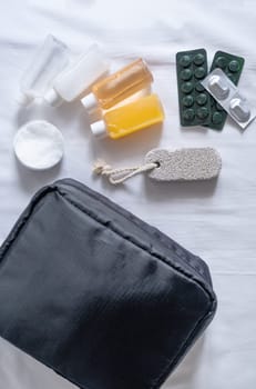 Travel cosmetics kit with bottles, pills and cosmetics on bed , top view