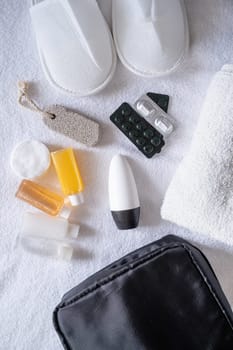 Travel cosmetics kit with bottles, pills and cosmetics on bed , top view