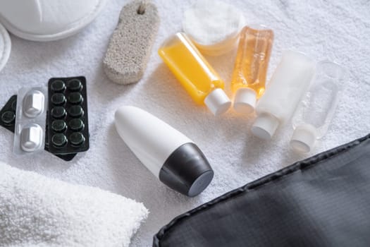 Travel cosmetics kit with bottles, pills and cosmetics on bed , top view