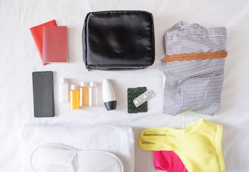 Travel cosmetics kit with bottles, pills and cosmetics on bed , top view
