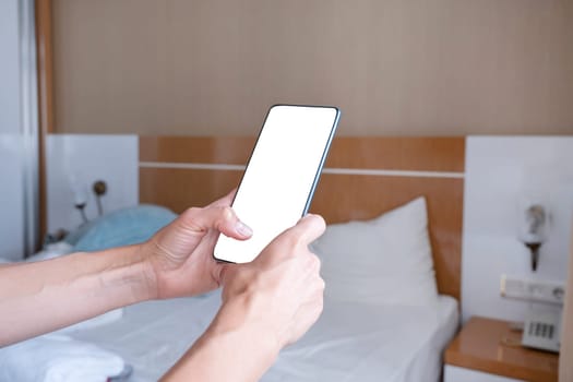 closeup of female hands using smartphone in hotel room , white blank screen for mockup