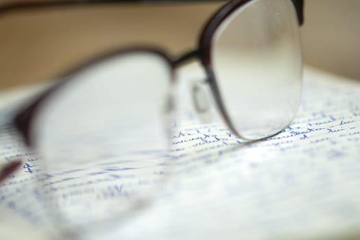 handwritten sheet with the writing seen through a pair of glasses