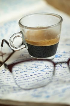 cup of coffee resting on an old handwritten manuscript