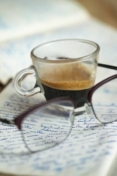 cup of coffee resting on an old handwritten manuscript