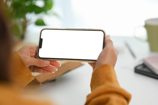 Woman in yellow sweater holding smartphone with empty screen. Closeup view.