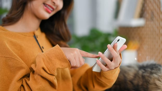 Cropped shot of smiling young woman texting message on mobile phone. People and technology concept.