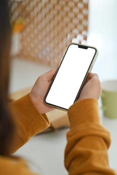 Woman in yellow sweater holding smartphone with empty screen. Closeup view.