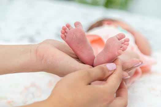 Close-up of the small legs of a newborn baby in the hands of a woman or mother. Moments with a child.