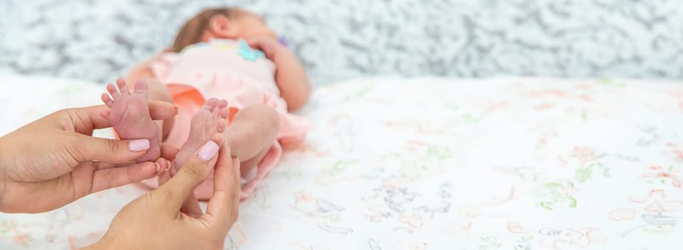 Close-up of the small legs of a newborn baby in the hands of a woman or mother. Moments with a child.