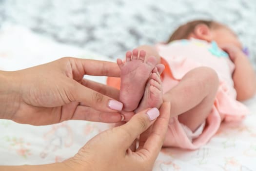 Close-up of the small legs of a newborn baby in the hands of a woman or mother. Moments with a child.