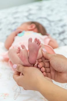 Close-up of the small legs of a newborn baby in the hands of a woman or mother. Moments with a child.