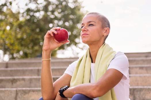 young sports woman rests eating an apple after a hard workout, concept of healthy and active lifestyle