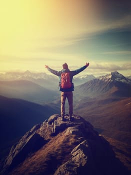 A man stands on top of a majestic mountain, arms wide open, embracing the exhilaration of conquering natures grandeur.