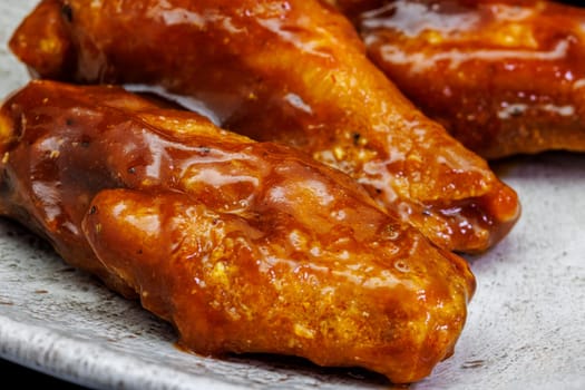 Composition of a plate of chicken wings with barbecue sauce on black background