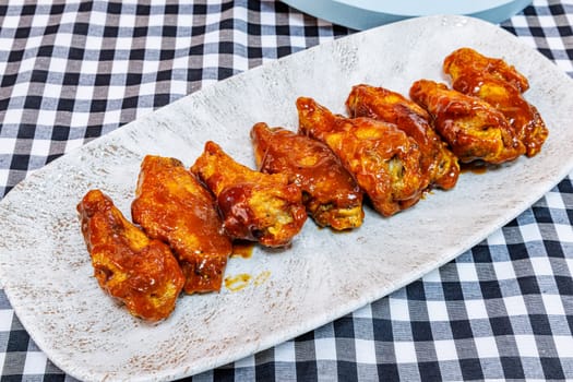 Composition of a plate of chicken wings with barbecue sauce on a black and white checkered tablecloth