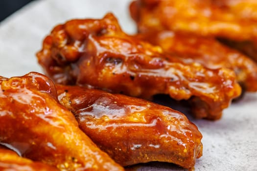 Composition of a plate of chicken wings with barbecue sauce on black background