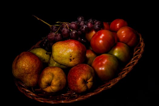 Composition of pears, tomatoes and grapes in a basket