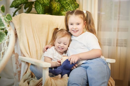 Happy time concept. Girls Sisters in chair and having fun. Female Preschooler and teenager playing and relaxing in room