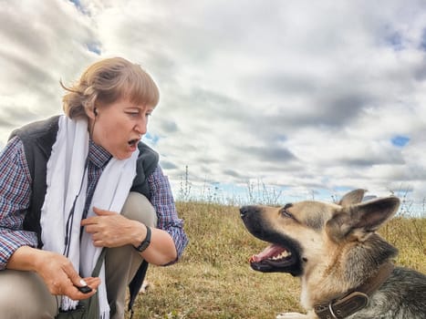 Adult girl with shepherd dog taking selfies in field. Middle aged woman and big shepherd dog on nature. Friendship, love, communication, fun, hugs