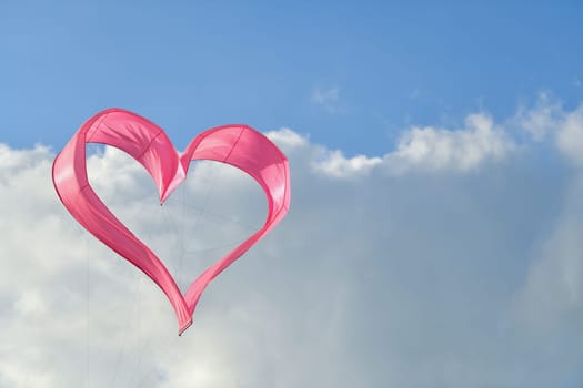 Pink heart kite is flying in the sky