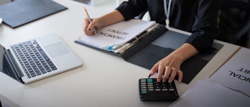 Businesswoman accountant using calculator and laptop for financial data saving in office room, Business financial, tax, accounting concept.