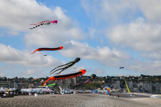 DIEPPE, FRANCE - SEPTEMBER 11, 2018: Kite festival. Octopus kites and flying caterpillar in the sky in the Atlantic ocean