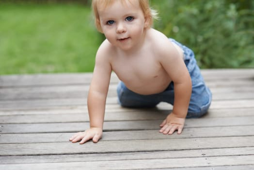 Baby, portrait on floor outdoor for development with relax, curiosity and early childhood in backyard of home. Toddler, child and crawling on ground for wellness, milestone and exploring with playing.