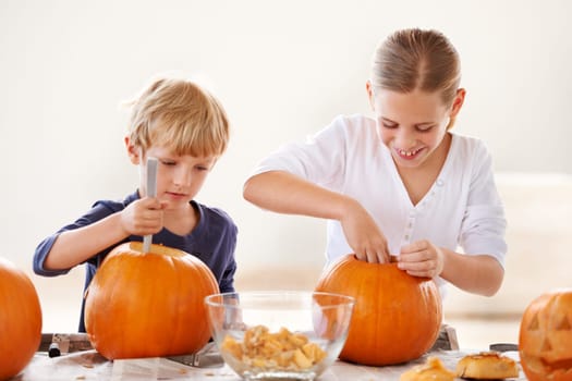 Sister, brother or happy with pumpkin for halloween, celebration or decoration in kitchen of apartment or home. Family, face or smile and vegetable for preparation, holiday or creative event in house.