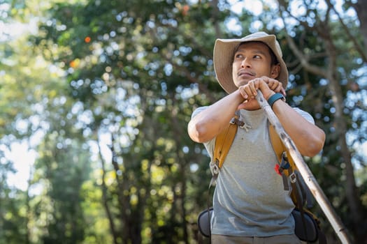 Young man asian trekking among trees with backpack, young man enjoy alone in forest. Camping, hiking, travelling, search for adventure concept.