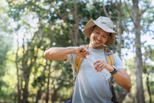 Traveler hiking man carrying a backpack on the back and walking in national park. man asian is rest by drink water.