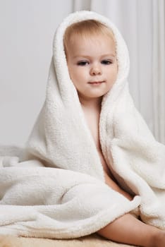 Portrait of baby on bed, clean with towel and bath in morning with health, wellness and growth in house. Cute happy toddler in bedroom for hygiene, relax or calm bedtime for child development in home.