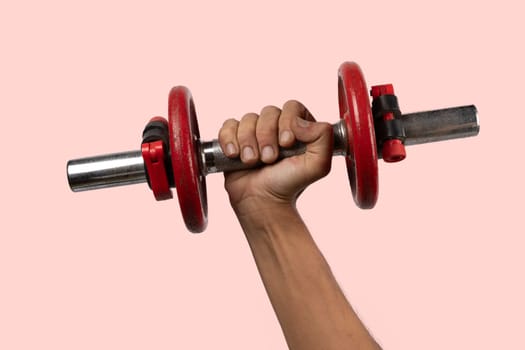 Black male hand holding metal and red dumbbell on pink background. High quality photo