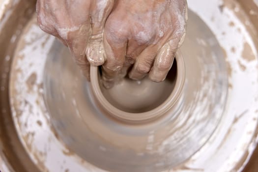 male hands making ceramic cup on pottery wheel, Close-up, top view