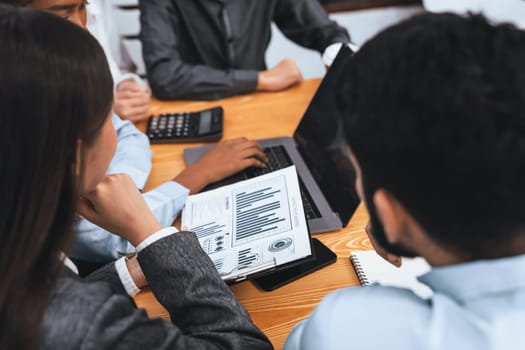 Multiracial analyst team use BI dashboard data to analyze financial report on meeting table. Group of diverse business people utilize data analysis by FIntech for business marketing decision. Concord