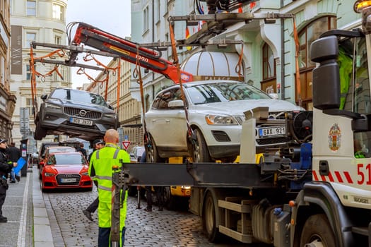 Two cars are taken away by a tow truck, improper parking in the city center. Parking inspection.