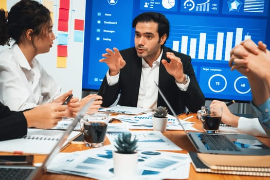 Diverse group of business analyst team analyzing financial data report. Finance data analysis chart and graph dashboard show on TV screen in meeting room for strategic marketing planning. Habiliment