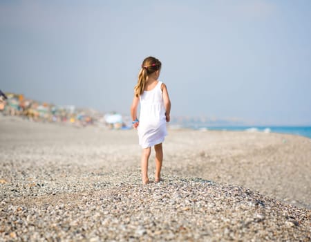 Back of a little girl on tropical beach vacation