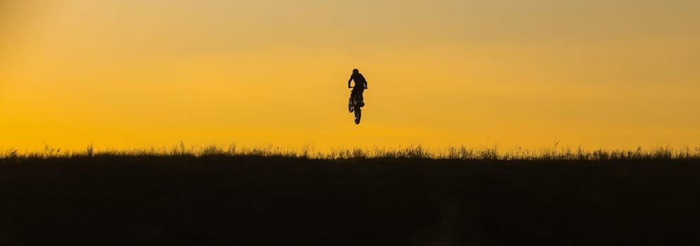 motocross at sunset silhouette of a motorcycle on the field. High quality photo