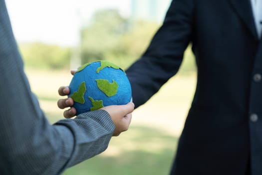 Earth day concept, businessman giving Earth globe to colleague as CSR corporate social responsible principle to promote environmental awareness and embrace ESG for greener and sustainable future. Gyre
