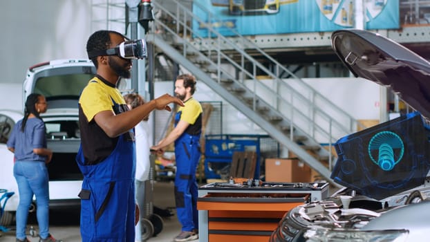 Certified engineer in repair shop using advanced virtual reality technology to visualize car mechanical component in order to fix it. Garage expert wearing vr glasses while mending broken vehicle